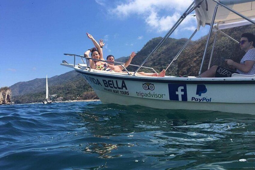 A boat named 'Bella' with 'tripadvisor' and 'PayPal' logos, sailing on water with a mountainous landscape in the background. 1