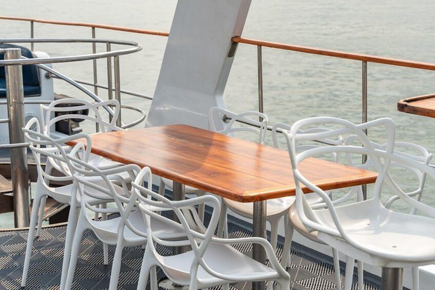 A deck with white plastic chairs and a wooden table, overlooking calm water. 4