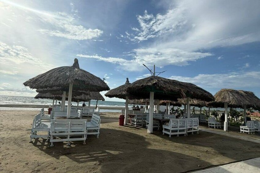 Sombrillas de playa, sillas de descanso blancas y una playa arenosa. 4