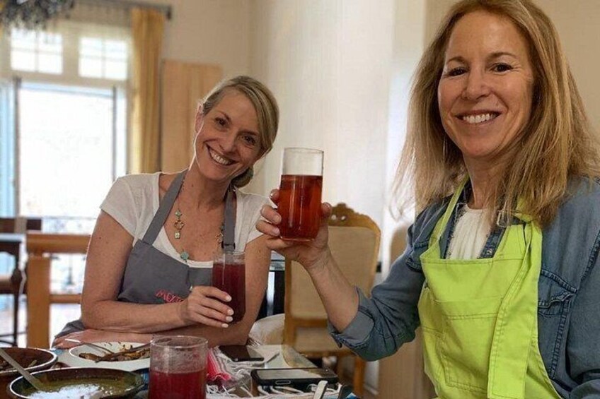 Deux personnes tenant des verres contenant une boisson rouge, avec une table au premier plan. 4