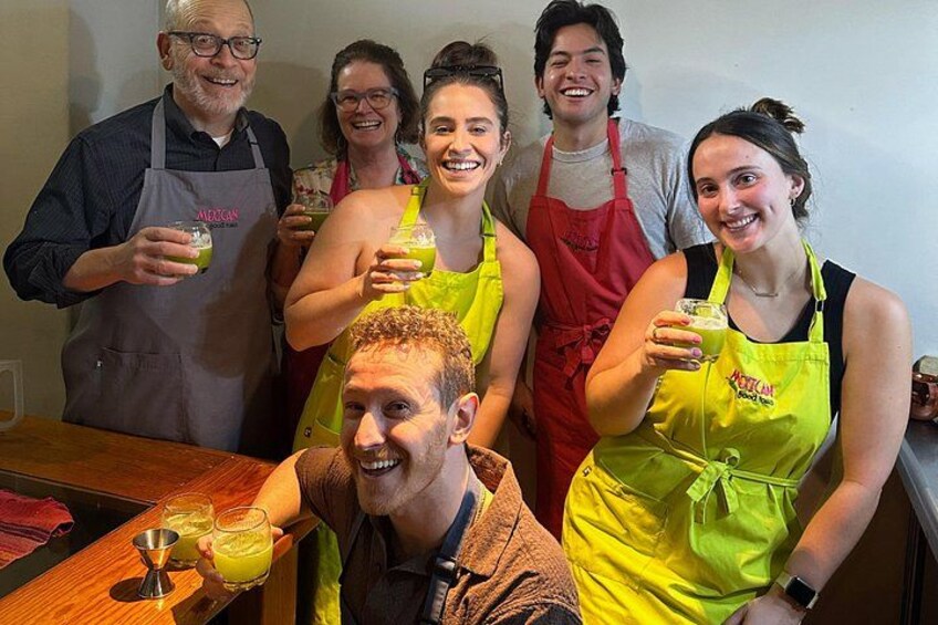 Un grupo de personas con mandiles sosteniendo bebidas, con una barra y vasos en primer plano. 1