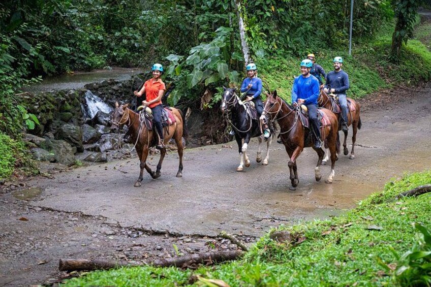 Un groupe de personnes à cheval, évoluant sur un chemin boueux, entouré d’une végétation luxuriante. 4