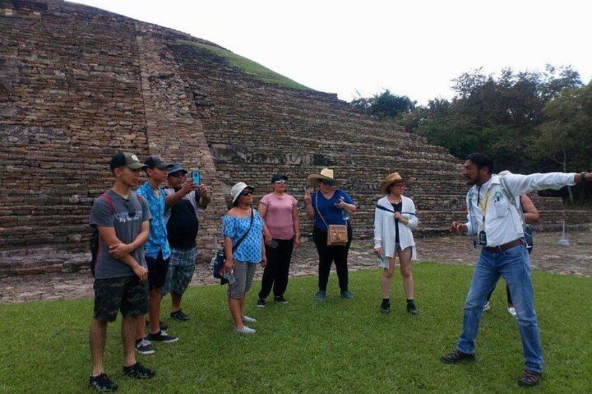 A group of people standing in front of an ancient stone structure. 5