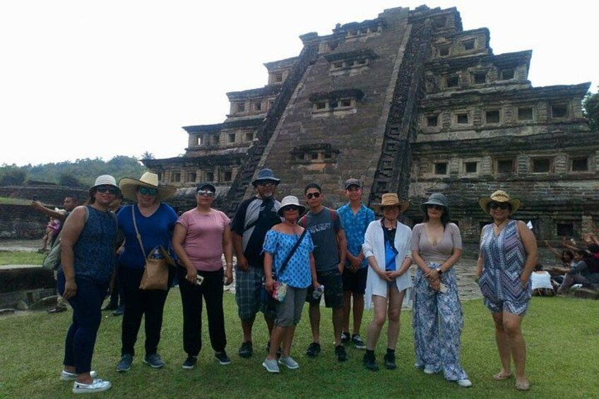 A group of people standing in front of a large ancient pyramid structure. 4