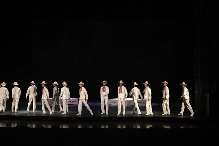 A group of people in white outfits and hats walking on a stage. 2