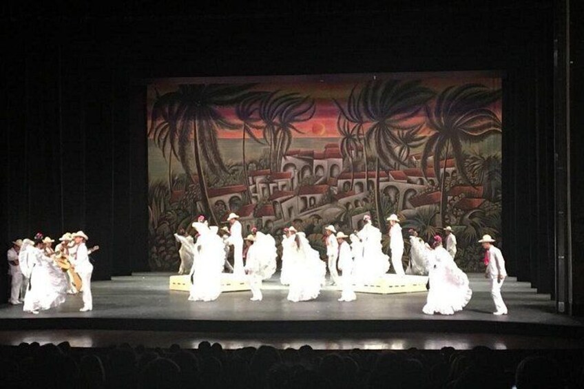 A stage with a group of people in white costumes performing a dance. 4