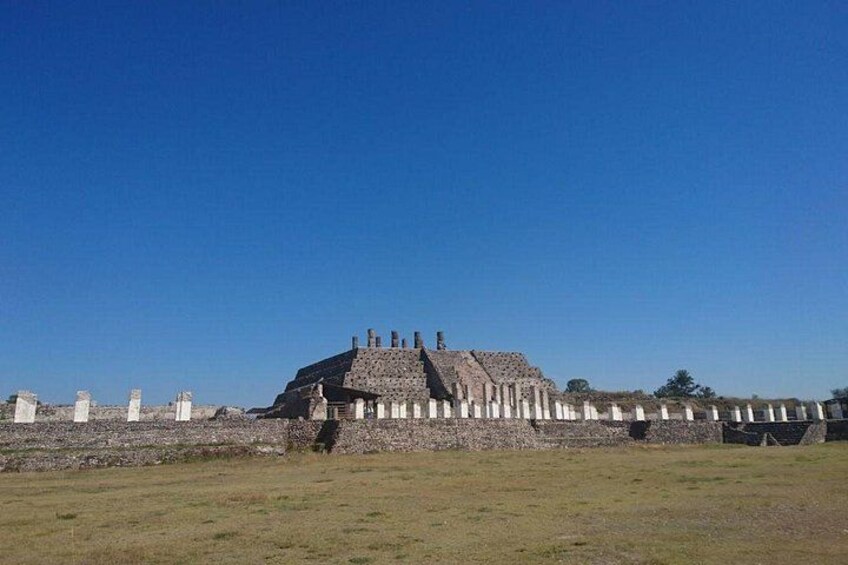 An ancient pyramid-like structure with a flat top and staircases on the sides, surrounded by a low wall. 1