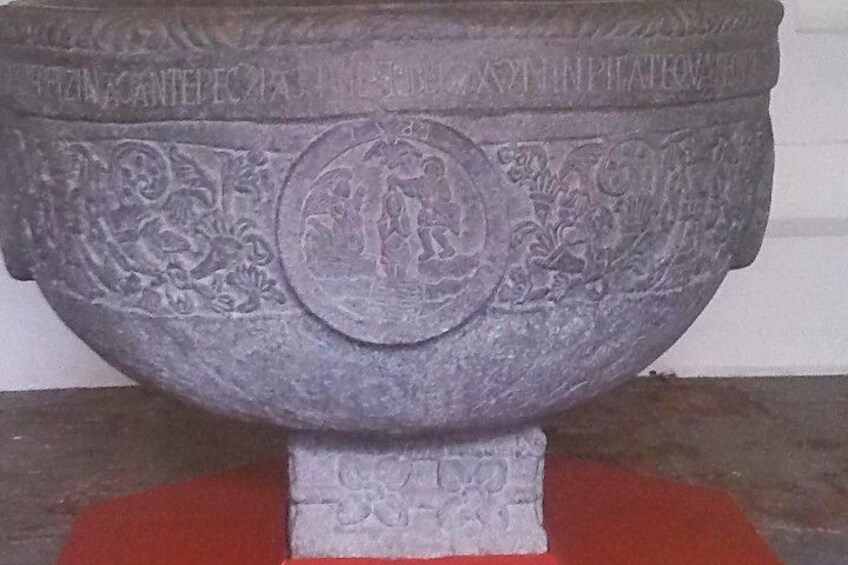 A large stone basin with intricate carvings and inscriptions, placed on a pedestal. 3