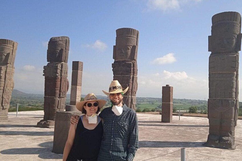 A couple standing in front of ancient stone columns with a clear sky in the background. 4