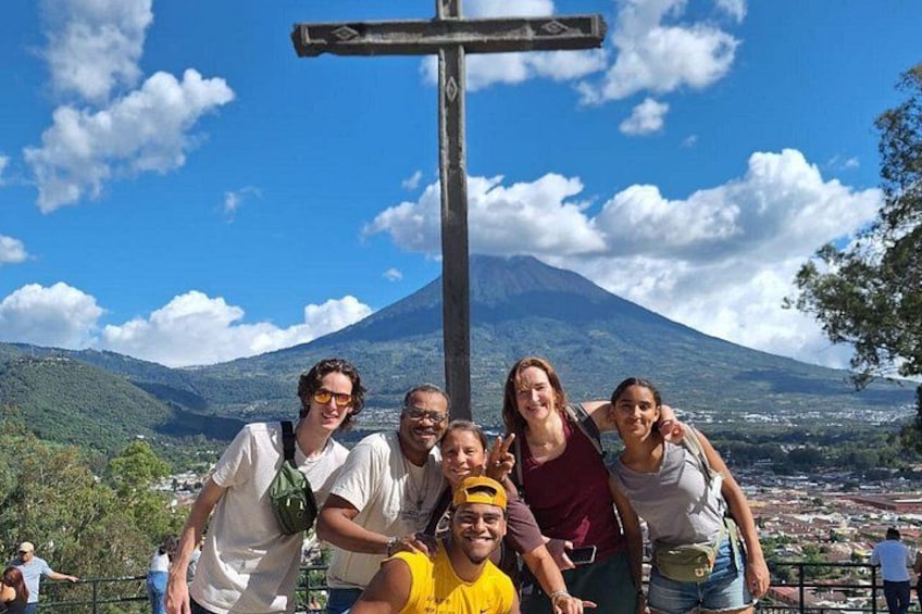 A group of people posing in front of a cross with a mountain in the background. 2