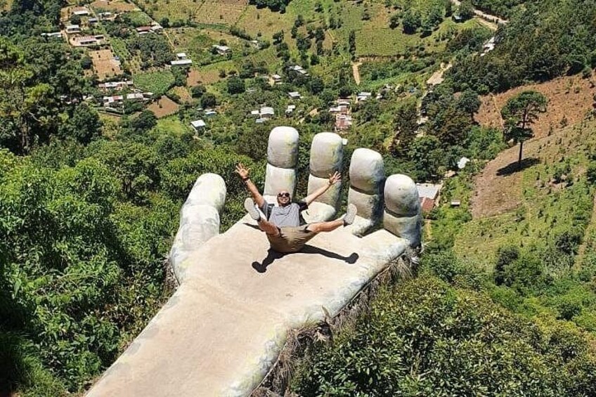 Une personne assise sur une bordure de béton, avec un paysage rural en arrière-plan. 2