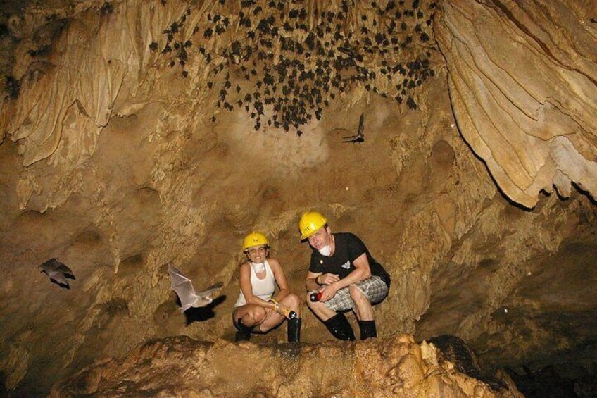 Two people in a cave with stalactites and stalagmites. 1