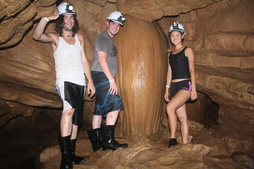 Three people in a cave with a large stalactite formation. 4