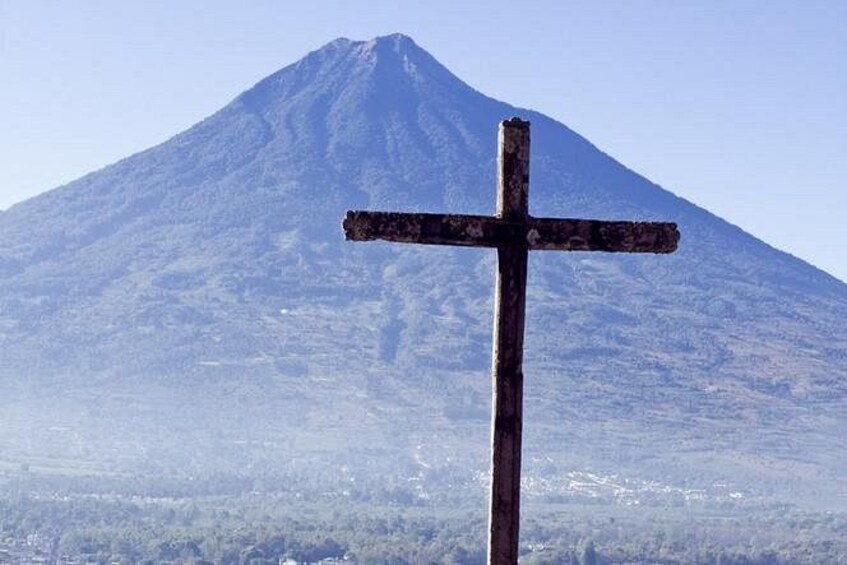 A wooden cross in front of a mountain. 3