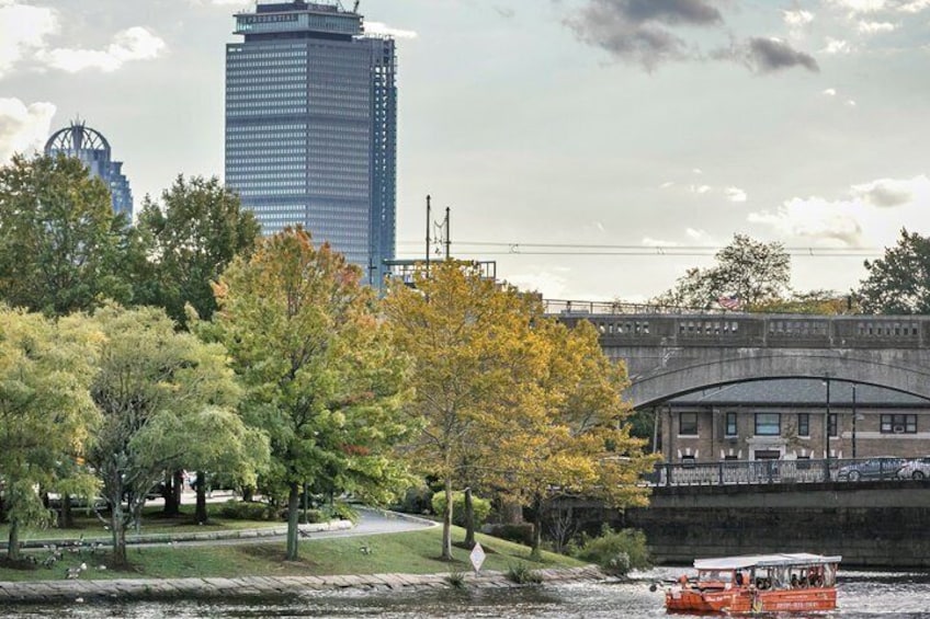 Un río con un bote, un puente, un edificio y árboles con follaje otoñal. 2