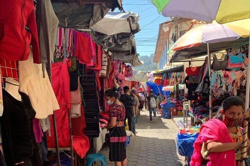 Un mercado al aire libre animado con varios puestos que ofrecen ropa colorida. 1