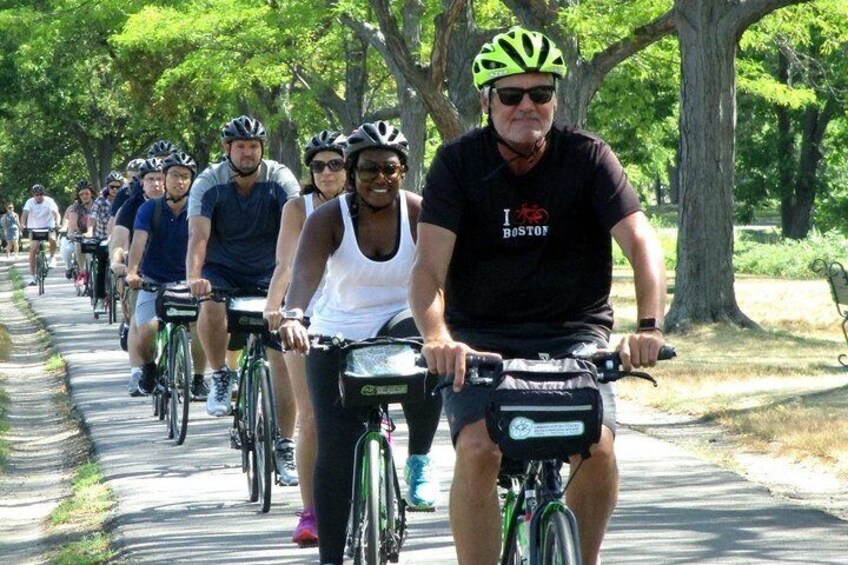 A group of cyclists on a tree-lined path. 1