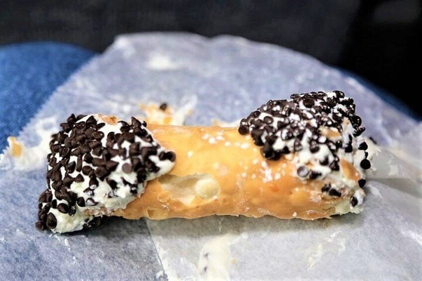 A pastry with chocolate chips and a creamy filling on a piece of parchment paper. 2