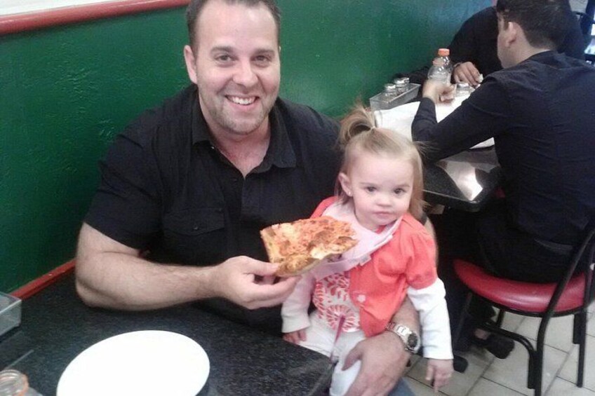 A man and a child at a table with pizza. 3