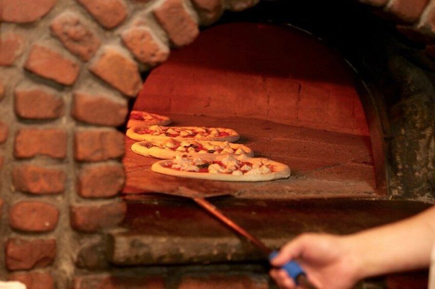 A brick oven with pizzas being cooked inside. 5