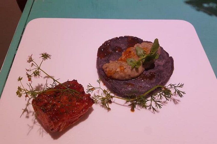 A plate with a purple puree, a piece of meat, and some herbs. 4