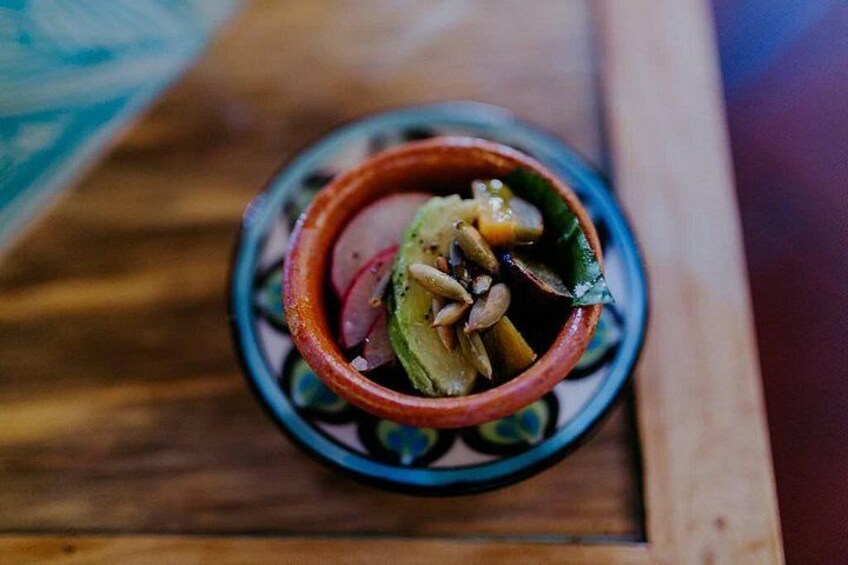 A bowl of food with vegetables and nuts on a wooden surface. 5