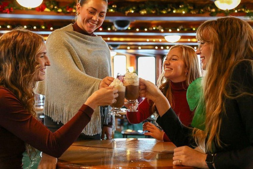 A group of people toasting with drinks at a bar with festive decorations. 2