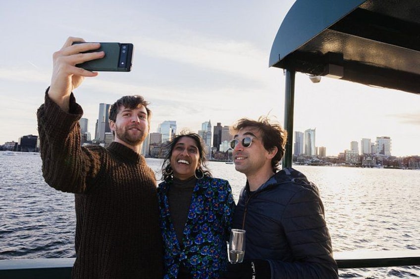 Trois personnes se trouvent sur un bateau, avec la silhouette d’une ville en arrière-plan. 3