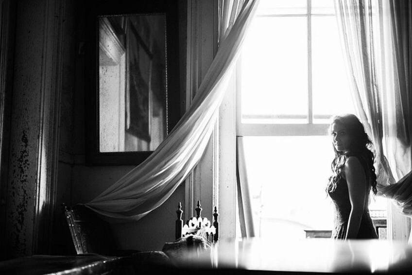 A room with a large window, draped curtains, and a table with a candle. 3