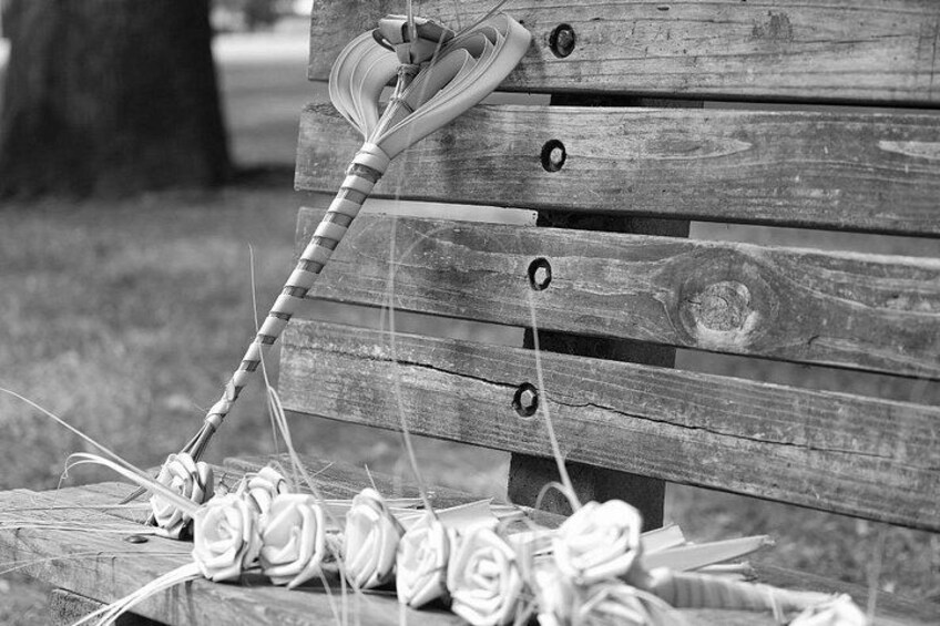 A wooden bench with a shoe and a string of flowers. 4