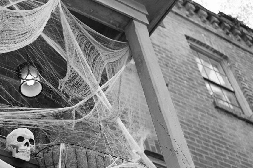 A brick building with a wooden porch, a hanging hammock, and a skull decoration. 2