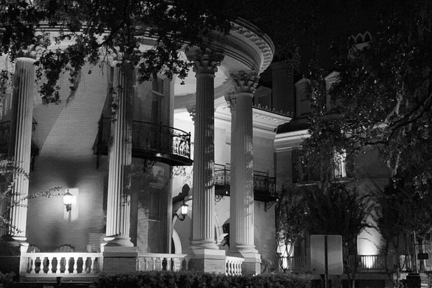A grand building with large columns and a balcony, illuminated at night. 4