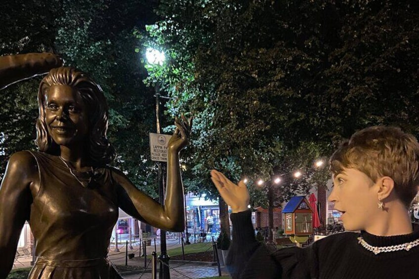 A statue of a woman holding a sign, with a person in the foreground. 5