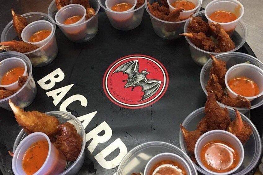 A food display with fried items and sauce cups, and a logo with a bat and the word 'BACARDI'. 4