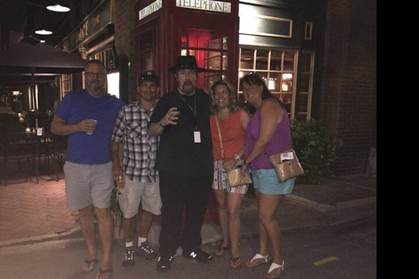 A group of people standing outside a building with a sign that reads 'TELEPHONE.' 2
