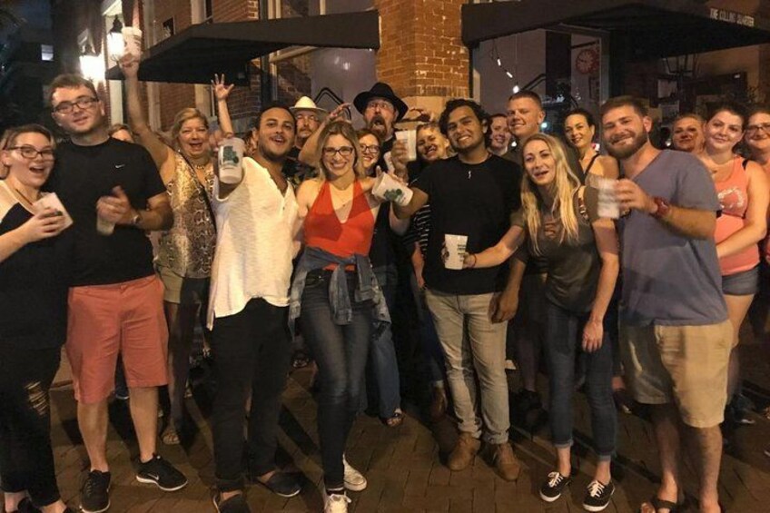 A group of people posing for a photo on a city street at night. 5