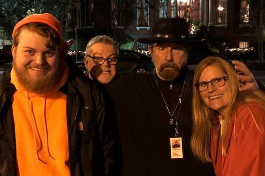 Three people standing outdoors at night with a building in the background. 4