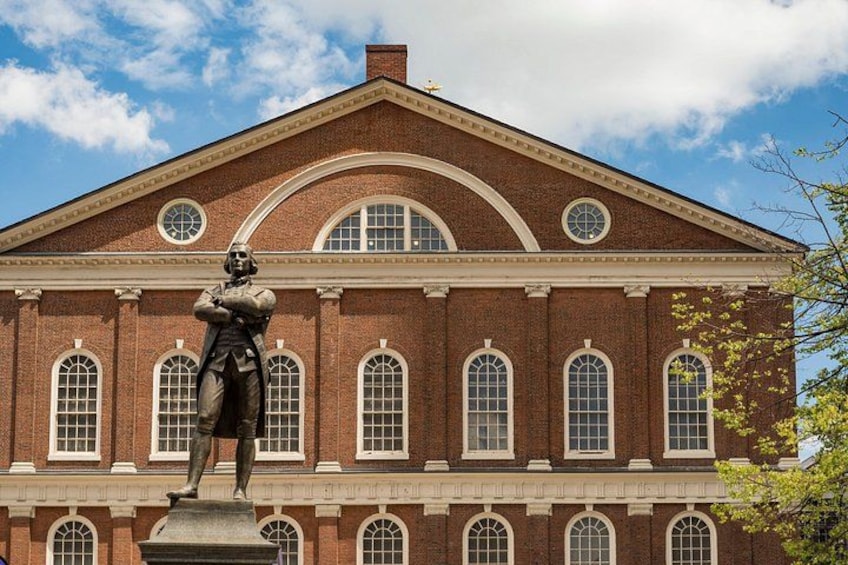 A red brick building with arched windows and a statue in front. 5
