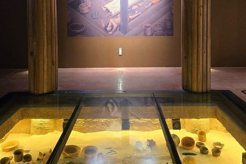 Une exposition de musée présentant des poteries et une projection vidéo montrant des mains travaillant la poterie. 2