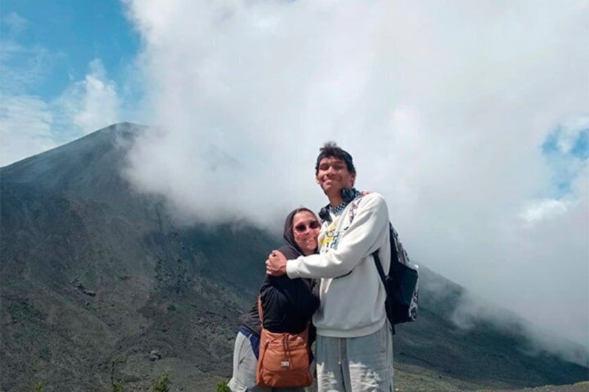 Two people embracing on a mountain with clouds above. 4