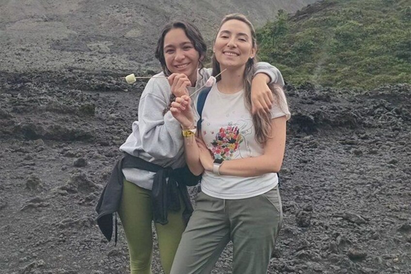 Dos personas de pie sobre un terreno rocoso con montañas al fondo. 3