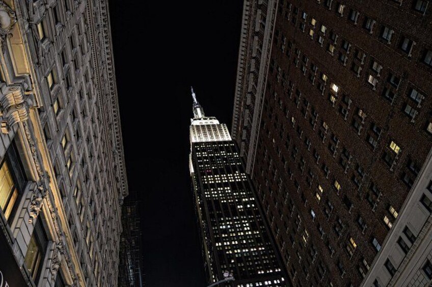 Vista nocturna de un edificio alto con ventanas iluminadas y una aguja. 3