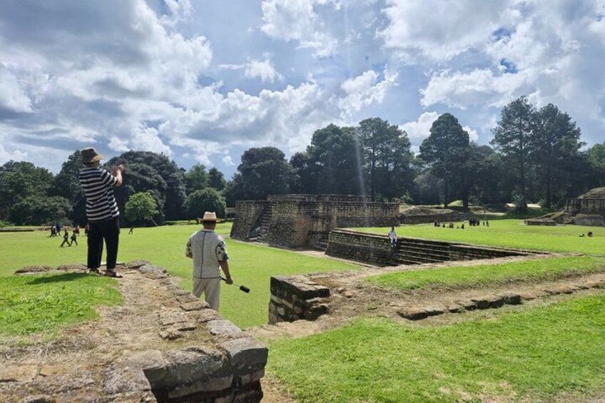 A historical site with ruins, a grassy area, and visitors. 4