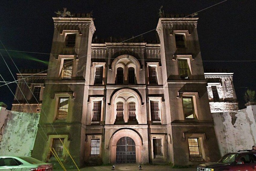 Un bâtiment historique doté d’arcs en plein cintre et d’une porte d’entrée centrale, illuminé la nuit. 1