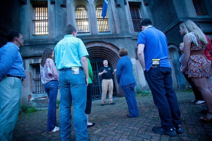 Un groupe de personnes se tient devant un bâtiment historique doté d’arcades et d’une grande entrée. 3