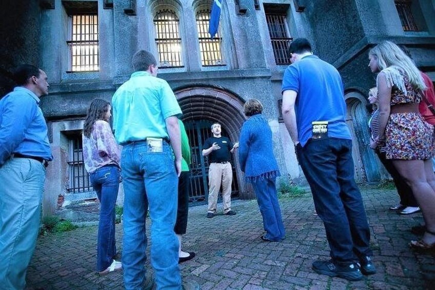 Un groupe de personnes se tient devant un bâtiment historique doté d’arcades et d’une grande entrée. 2