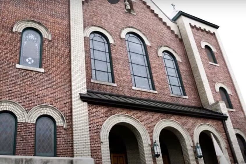 En murstensbygning med buede vinduer og et kors øverst. 4