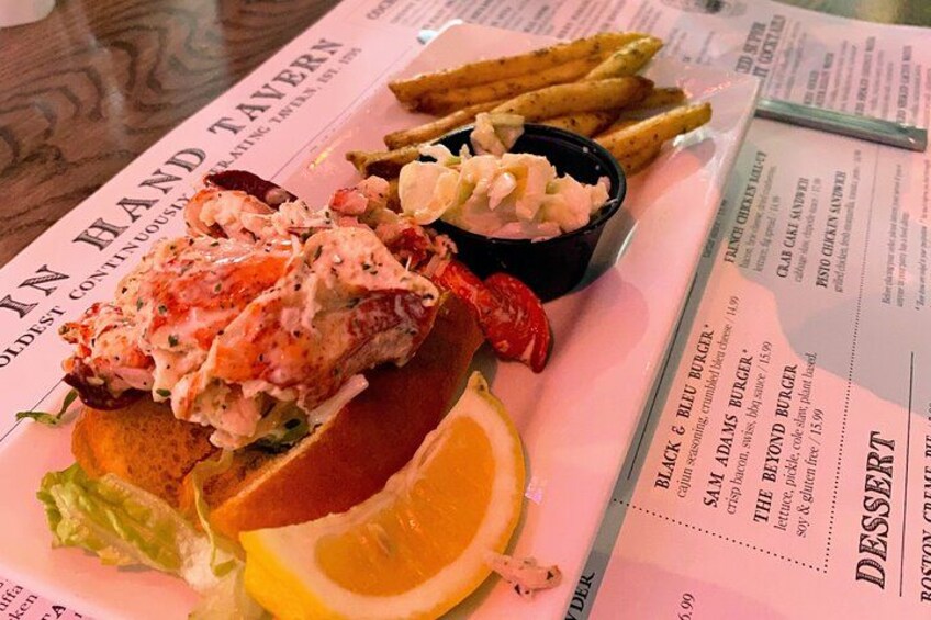A lobster roll with fries and a side salad on a menu. 3