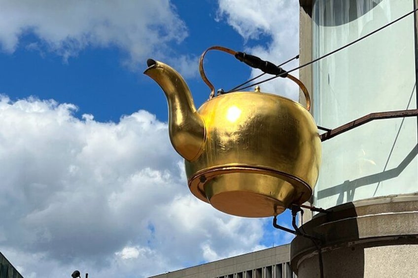 Een gouden theepot bevestigd aan een gebouw. 5