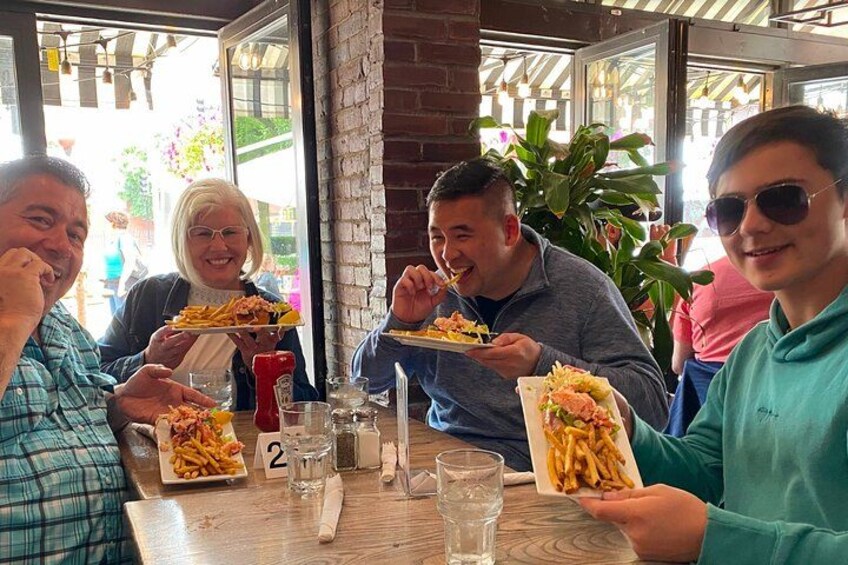 A group of people dining at a restaurant with plates of food and drinks on the table. 1